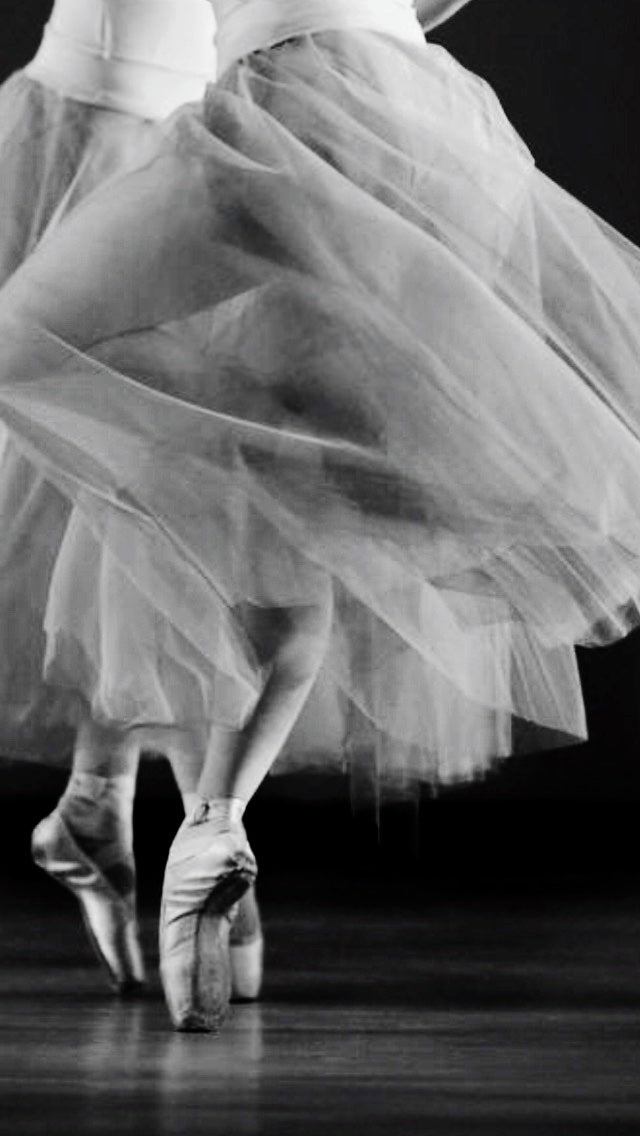 Ballerina in a tutu and pointe shoes on a dark background